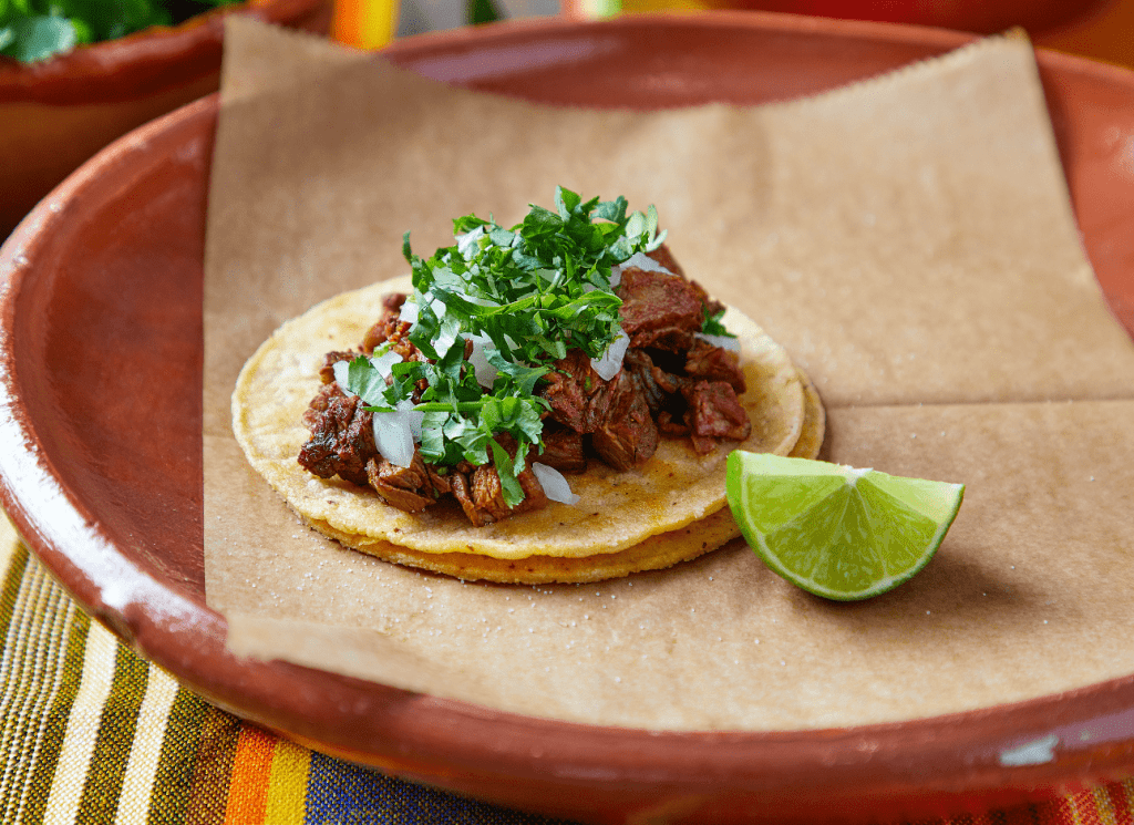 Steak Adobada taco with marinated steak, onions, and cilantro on a double corn tortillaa